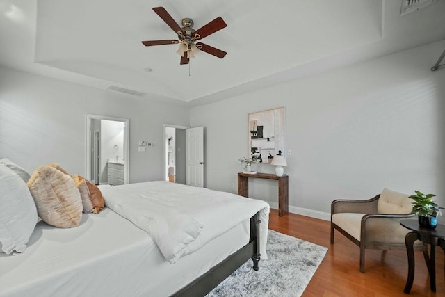 2425 Sir Lovel Ln, Lewisville, TX 75056 - bedroom with a tray ceiling, light wood-style flooring, baseboards, ensuite bath, and a ceiling fan