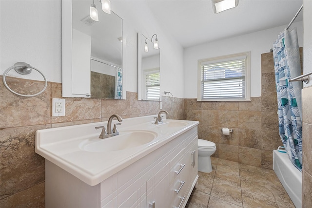 1025 N 32nd St, Waco, TX 76707 - bathroom with tile walls, double vanity, toilet, shower / bath combo, and a wainscoted wall