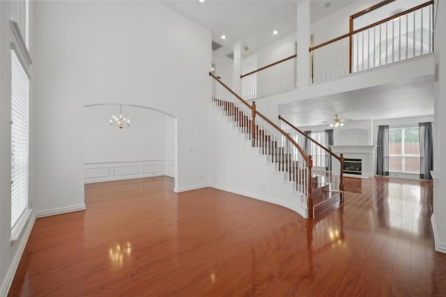 518 Hawthorne Dr, Murphy, TX 75094 - unfurnished living room featuring a high ceiling, stairs, wood finished floors, ceiling fan, and a glass covered fireplace