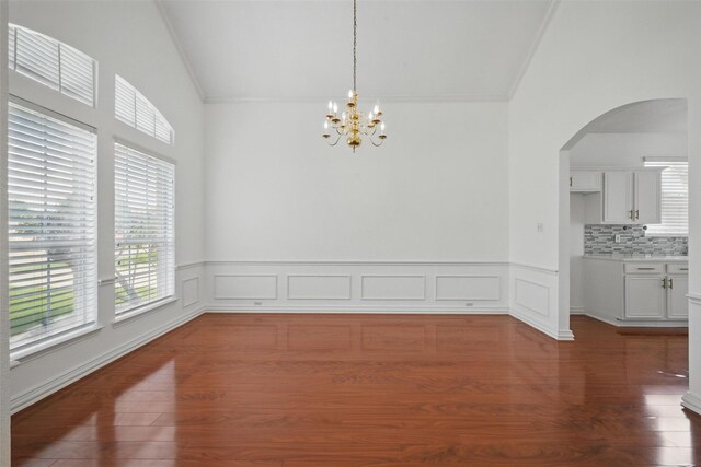 518 Hawthorne Dr, Murphy, TX 75094 - unfurnished dining area featuring arched walkways, crown molding, dark wood-type flooring, a chandelier, and vaulted ceiling