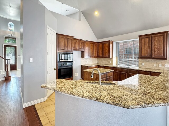 5973 Country View Ln, Frisco, TX 75036 - kitchen with oven, a sink, stainless steel microwave, high vaulted ceiling, and light stone counters
