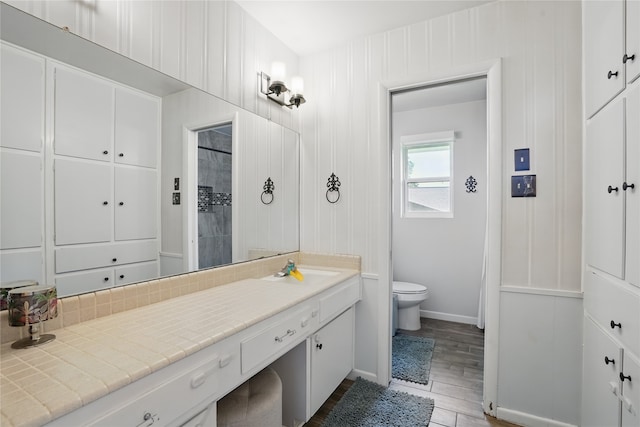 3720 Wharton Dr, Fort Worth, TX 76133 - bathroom featuring vanity, toilet, wood finished floors, tiled shower, and baseboards