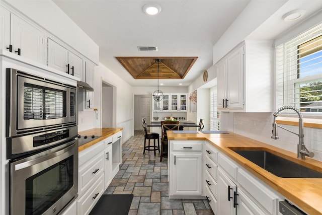 529 Doubletree Dr, Highland Village, TX 75077 - kitchen featuring butcher block countertops, appliances with stainless steel finishes, a sink, stone finish floors, and white cabinets