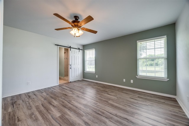 505 W Thomas St, Leonard, TX 75452 - unfurnished room with a barn door, ceiling fan, wood finished floors, and baseboards