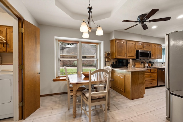 2818 Summit Ridge St, Grapevine, TX 76051 - kitchen featuring washer / clothes dryer, appliances with stainless steel finishes, brown cabinetry, a peninsula, and ceiling fan