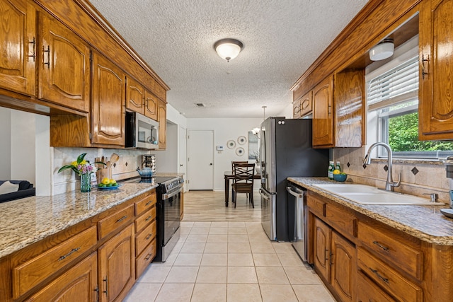 140 Amory Dr, Benbrook, TX 76126 - kitchen featuring stainless steel appliances, a textured ceiling, a sink, backsplash, and brown cabinetry