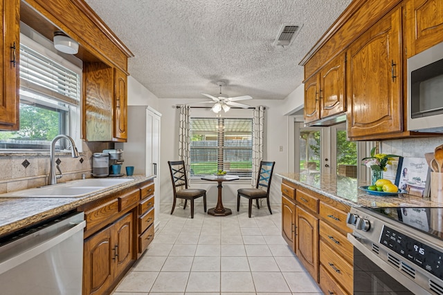 140 Amory Dr, Benbrook, TX 76126 - kitchen featuring stainless steel appliances, a sink, backsplash, light tile patterned floors, and a textured ceiling