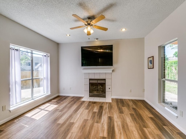 750 Pulitzer Ln, Allen, TX 75002 - unfurnished living room featuring a fireplace, wood finished floors, a textured ceiling, ceiling fan, and baseboards
