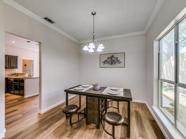 750 Pulitzer Ln, Allen, TX 75002 - dining room with light wood-type flooring, ornamental molding, a chandelier, baseboards, and a textured ceiling