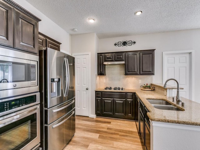 750 Pulitzer Ln, Allen, TX 75002 - kitchen with appliances with stainless steel finishes, a sink, light stone counters, a textured ceiling, and light wood-style floors