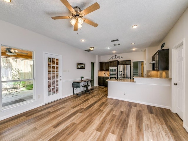 750 Pulitzer Ln, Allen, TX 75002 - kitchen featuring stainless steel appliances, light wood-type flooring, light countertops, a peninsula, and a textured ceiling