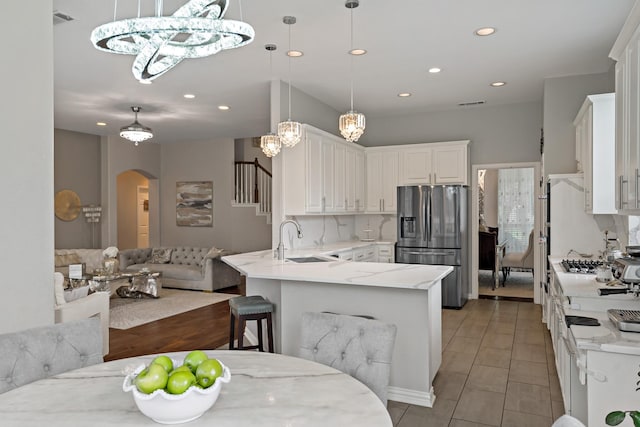 1912 White Oak Rd, Mckinney, TX 75072 - kitchen featuring stainless steel refrigerator with ice dispenser, arched walkways, a peninsula, recessed lighting, and open floor plan