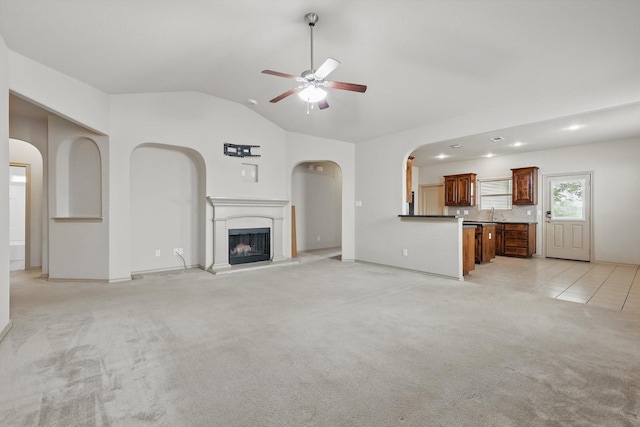 3512 Hornbeam St, Denton, TX 76226 - unfurnished living room featuring lofted ceiling, light carpet, ceiling fan, a fireplace with raised hearth, and arched walkways