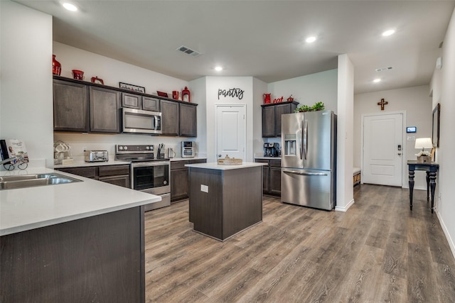 1316 Briar Hill Dr, Denton, TX 76207 - kitchen featuring appliances with stainless steel finishes, a kitchen island, a sink, dark brown cabinetry, and light countertops