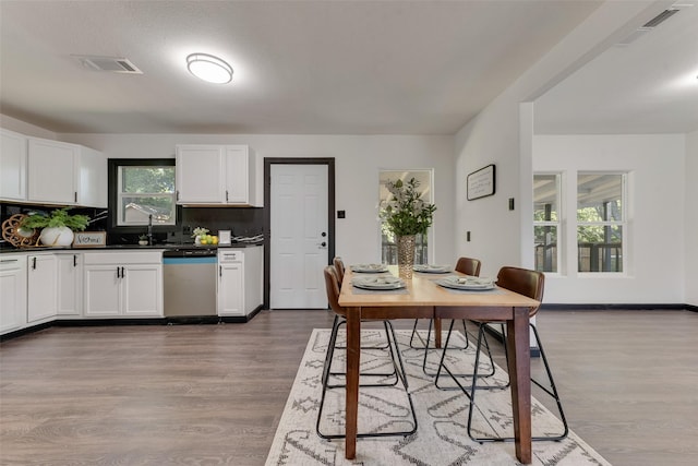 3467 Binyon St, Fort Worth, TX 76133 - kitchen with stainless steel dishwasher, wood finished floors, dark countertops, white cabinetry, and backsplash