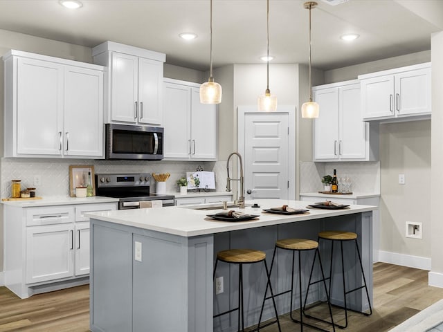 4416 Green Acres Ct, Arlington, TX 76017 - kitchen with stainless steel appliances, a sink, decorative backsplash, white cabinetry, and light wood-style floors