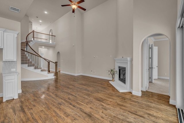 7819 Uxbridge Dr, Irving, TX 75063 - unfurnished living room with arched walkways, a high ceiling, ceiling fan, wood finished floors, and a glass covered fireplace