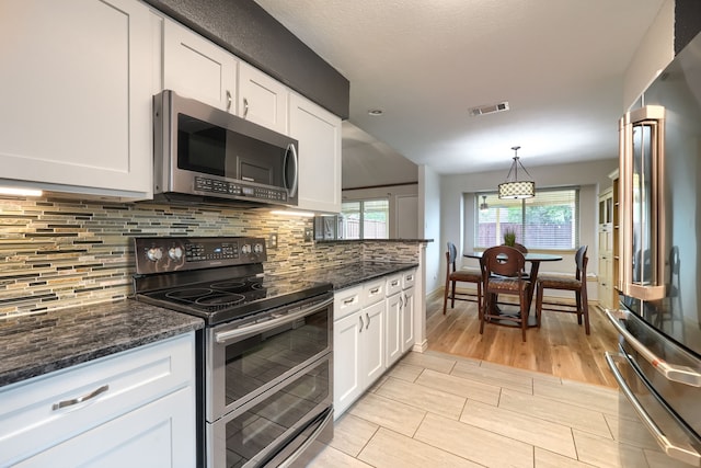 250 E Bancroft Dr, Garland, TX 75040 - kitchen featuring appliances with stainless steel finishes, white cabinetry, backsplash, and dark stone counters