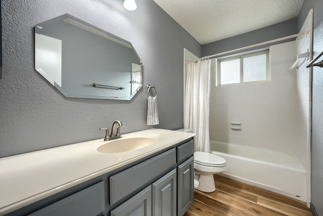 250 E Bancroft Dr, Garland, TX 75040 - full bathroom with wood finished floors, toilet, vanity, shower / bathtub combination with curtain, and a textured wall