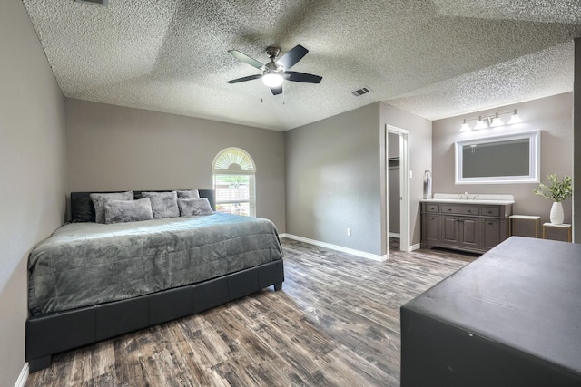 250 E Bancroft Dr, Garland, TX 75040 - bedroom featuring wood finished floors, a sink, baseboards, ceiling fan, and a textured ceiling