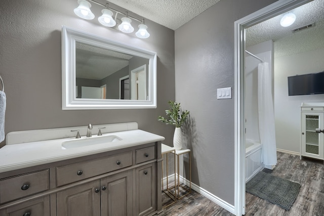 250 E Bancroft Dr, Garland, TX 75040 - full bathroom with a textured ceiling, wood finished floors, vanity, baseboards, and shower / tub combo