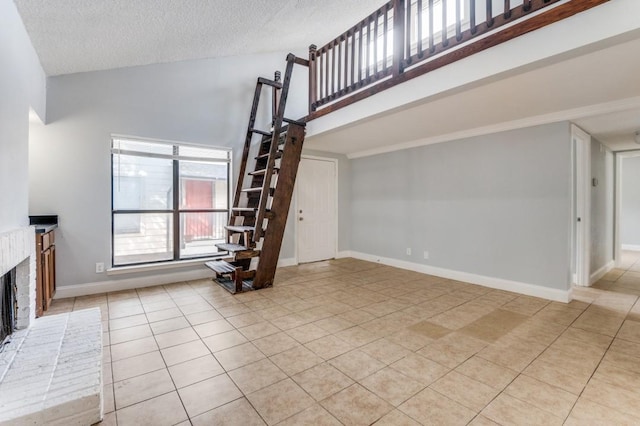 6646 E Lovers Ln Unit 1510, Dallas, TX 75214 - unfurnished living room with light tile patterned floors, high vaulted ceiling, a textured ceiling, a fireplace, and baseboards