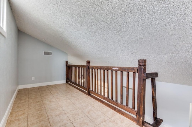 6646 E Lovers Ln Unit 1510, Dallas, TX 75214 - additional living space with a textured ceiling, lofted ceiling, light tile patterned floors, and baseboards
