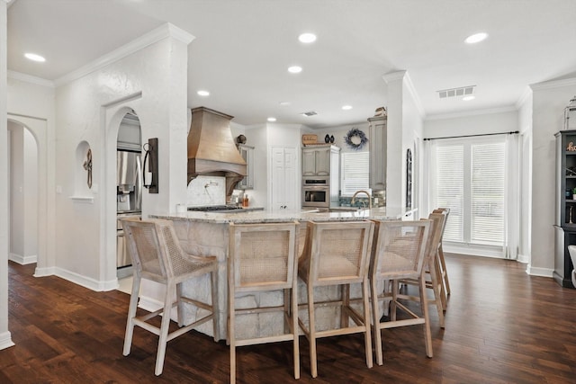 1000 Van Zandt Ct, Haslet, TX 76052 - kitchen with custom exhaust hood, stainless steel appliances, arched walkways, light stone countertops, and gray cabinets