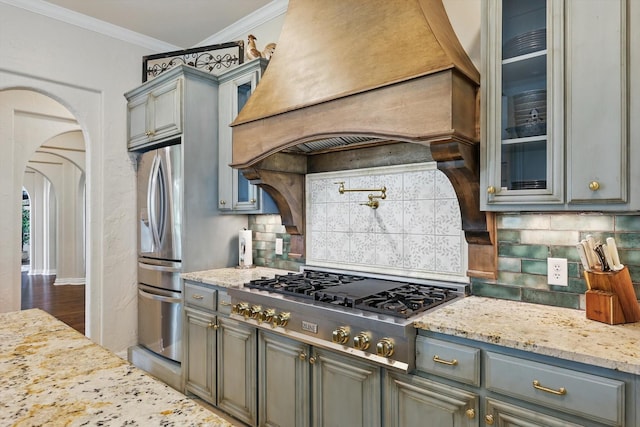 1000 Van Zandt Ct, Haslet, TX 76052 - kitchen featuring appliances with stainless steel finishes, custom range hood, arched walkways, gray cabinets, and glass insert cabinets