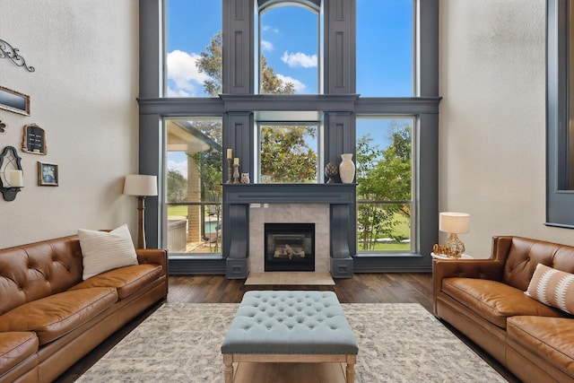 1000 Van Zandt Ct, Haslet, TX 76052 - living area with a textured wall, a high ceiling, a tiled fireplace, wood finished floors, and healthy amount of natural light