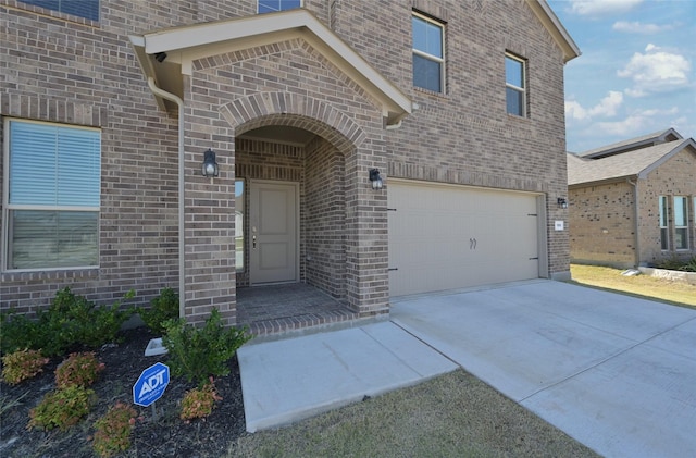 186 Dogwood Ave, Rhome, TX 76078 - doorway to property with brick siding, an attached garage, and concrete driveway