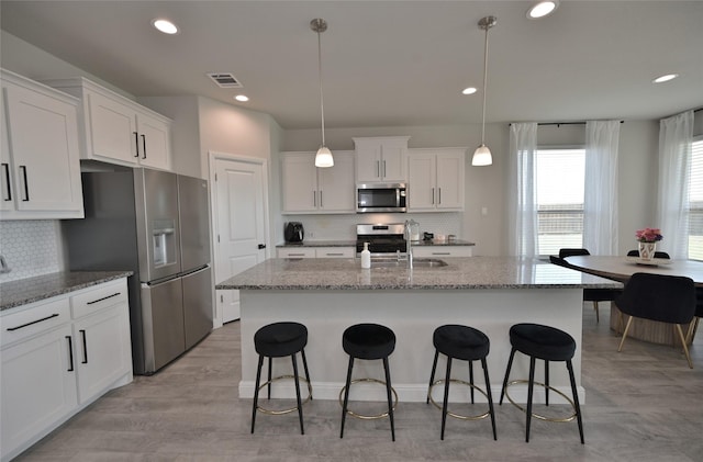 186 Dogwood Ave, Rhome, TX 76078 - kitchen featuring stainless steel appliances, decorative backsplash, white cabinets, a kitchen bar, and recessed lighting