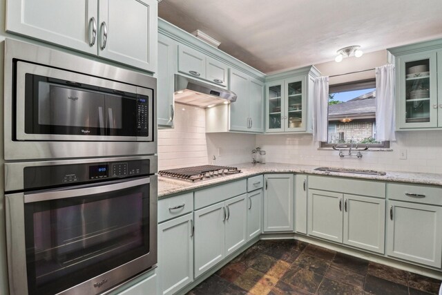 1113 Stanley St, Denton, TX 76201 - kitchen with appliances with stainless steel finishes, a sink, under cabinet range hood, tasteful backsplash, and light stone counters