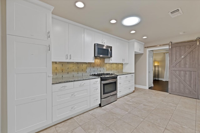 2612 Windsor Pl, Plano, TX 75075 - kitchen with stainless steel appliances, a barn door, tasteful backsplash, white cabinetry, and recessed lighting