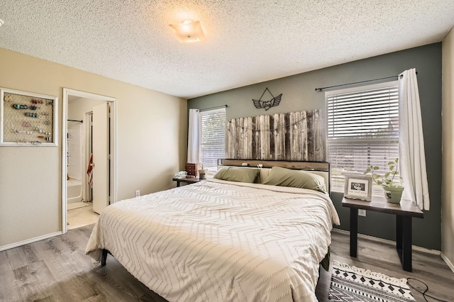 1806 Willowbrook Dr, Terrell, TX 75160 - bedroom featuring wood finished floors, a textured ceiling, baseboards, and ensuite bathroom
