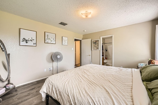 1806 Willowbrook Dr, Terrell, TX 75160 - bedroom with dark wood-style flooring, a textured ceiling, baseboards, and connected bathroom