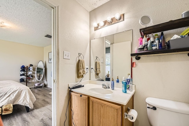 1806 Willowbrook Dr, Terrell, TX 75160 - bathroom featuring a textured ceiling, a textured wall, vanity, wood finished floors, and toilet