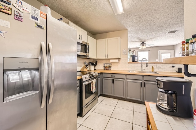 1806 Willowbrook Dr, Terrell, TX 75160 - kitchen with stainless steel appliances, a sink, gray cabinets, backsplash, and a ceiling fan