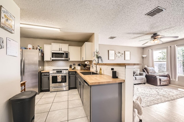 1806 Willowbrook Dr, Terrell, TX 75160 - kitchen with appliances with stainless steel finishes, a sink, butcher block counters, open floor plan, and gray cabinetry