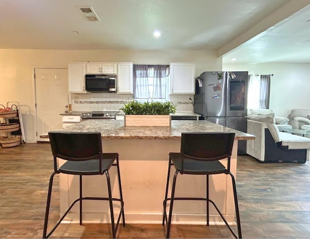 2300 Stoneman St, Dallas, TX 75215 - kitchen with stainless steel appliances, white cabinets, backsplash, dark wood finished floors, and light stone counters