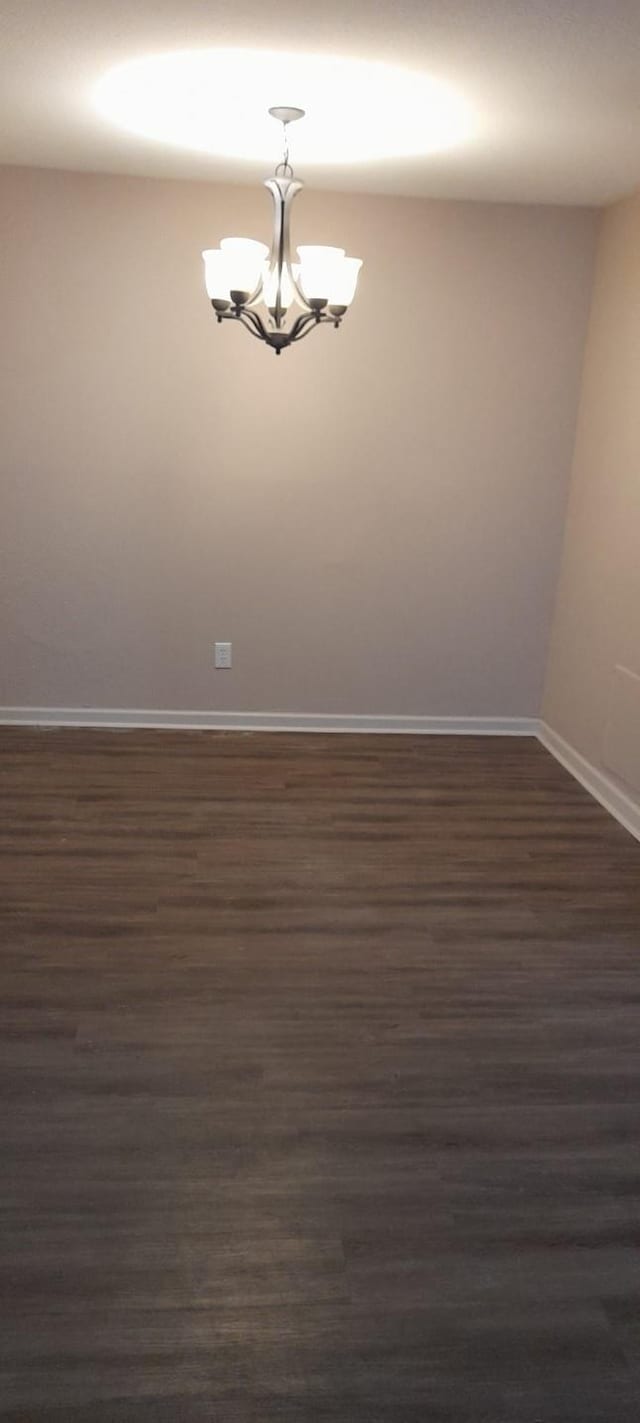 8110 Skillman St Unit 2054, Dallas, TX 75231 - empty room featuring a chandelier, baseboards, and dark wood finished floors