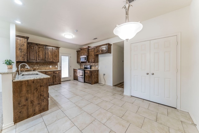 232 Lovers Path Dr, Springtown, TX 76082 - kitchen featuring stainless steel appliances, a sink, backsplash, light stone countertops, and dark brown cabinetry