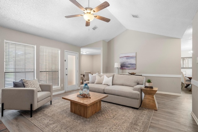 220 Timber Ridge Ln, Coppell, TX 75019 - living room with light wood-style flooring, a ceiling fan, vaulted ceiling, baseboards, and a textured ceiling