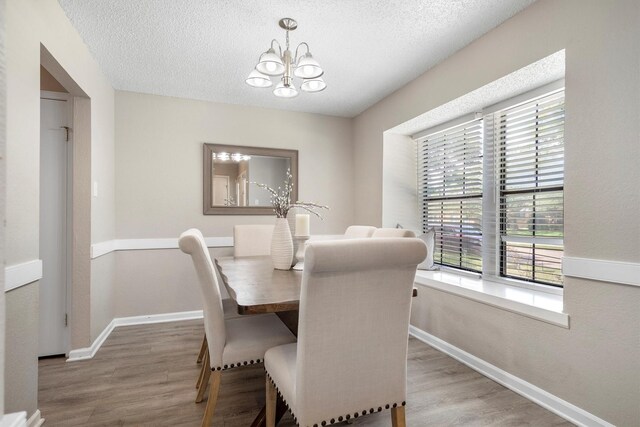 220 Timber Ridge Ln, Coppell, TX 75019 - dining area featuring a chandelier, healthy amount of natural light, wood finished floors, a textured ceiling, and baseboards