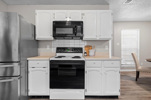 220 Timber Ridge Ln, Coppell, TX 75019 - kitchen with black microwave, electric range oven, freestanding refrigerator, white cabinetry, and tasteful backsplash