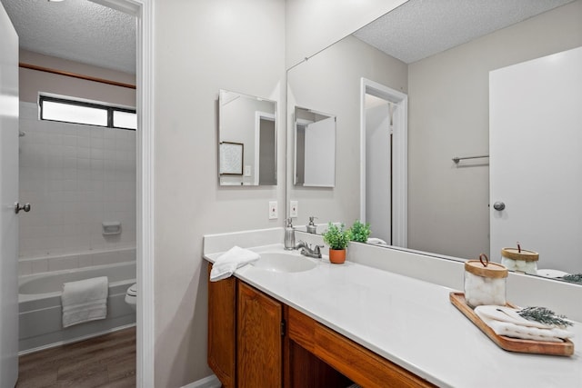 220 Timber Ridge Ln, Coppell, TX 75019 - bathroom with a textured ceiling, wood finished floors, toilet, vanity, and tub / shower combination