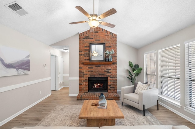 220 Timber Ridge Ln, Coppell, TX 75019 - living room featuring light wood-type flooring, vaulted ceiling, ceiling fan, a brick fireplace, and baseboards