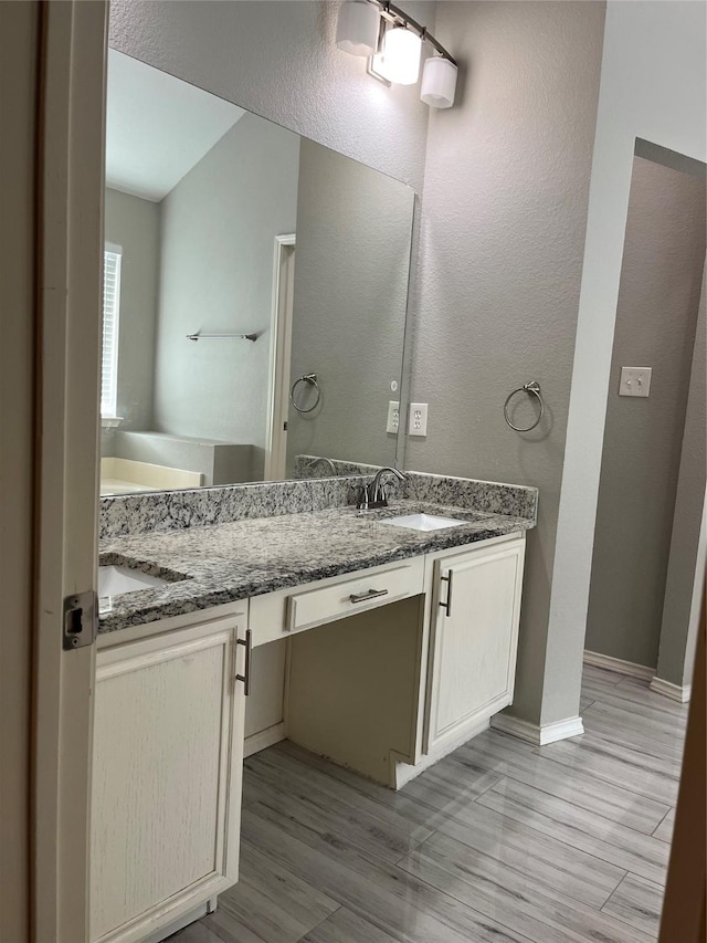 2020 Southwood Trl, Grand Prairie, TX 75052 - bathroom featuring double vanity, wood finished floors, a garden tub, and a textured wall