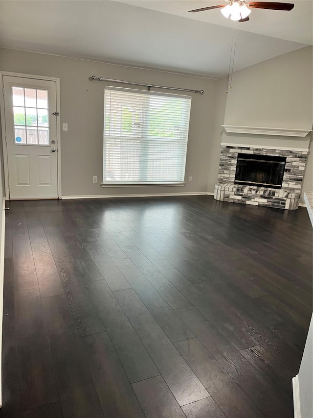 2020 Southwood Trl, Grand Prairie, TX 75052 - unfurnished living room featuring a ceiling fan, a stone fireplace, dark wood finished floors, and baseboards