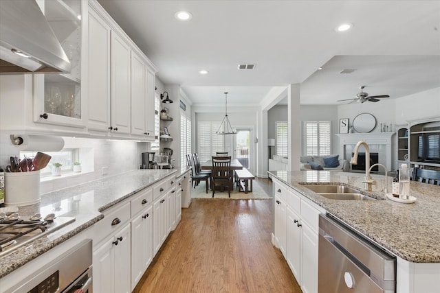 128 Brown Knight Ln, Lewisville, TX 75056 - kitchen with stainless steel appliances, ventilation hood, a sink, white cabinetry, and light wood-type flooring